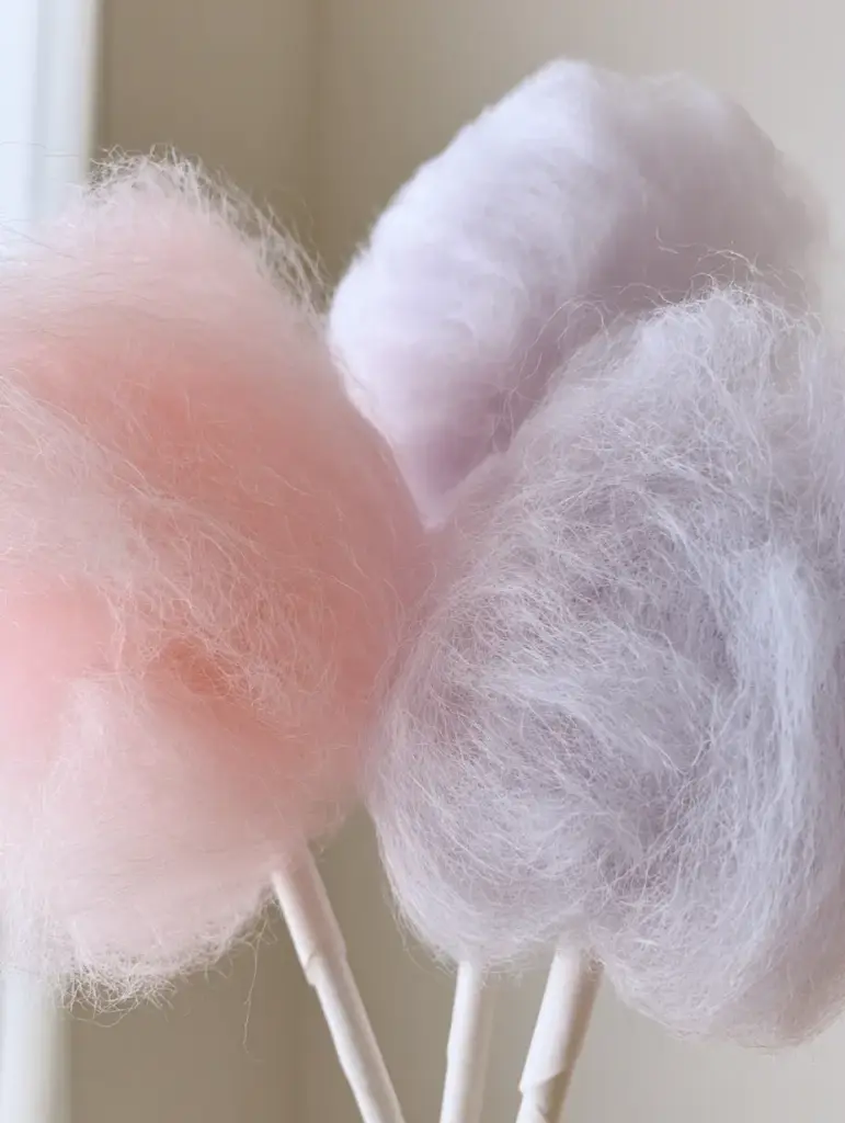 Homemade Cotton Candy: How to Make Fluffy Spun Sugar at Home 1 Airy mounds of lavender cotton candy on paper sticks in natural daylight.