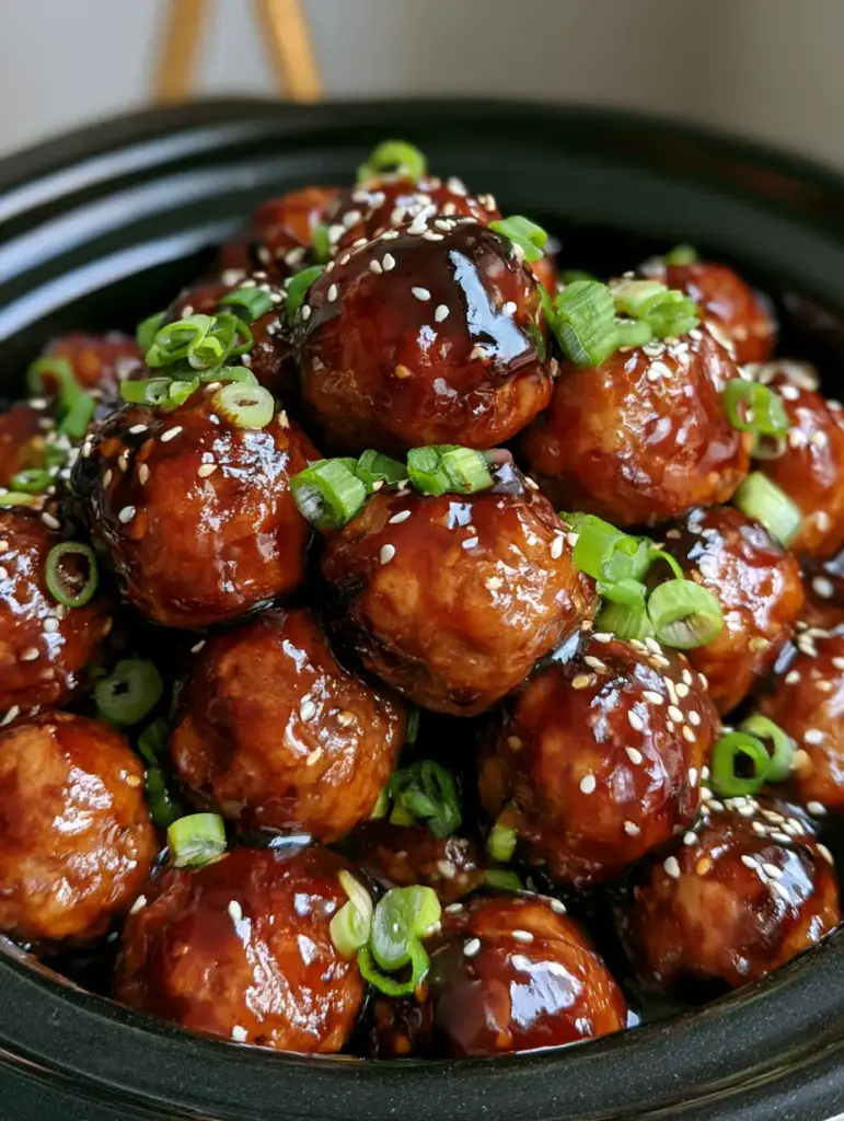 Slow Cooker Teriyaki Meatballs with a Thick Glossy Glaze 2 Close up smartphone photo of meatballs in a slow cooker with a dark syrupy glaze and heavy sesame seed garnish. (Slow Cooker Teriyaki Meatballs)